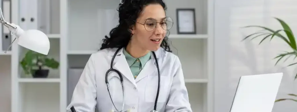 medica-olhando-para-seu-computador-com-uma-expressao-feliz medica-olhando-para-seu-computador-com-uma-expressao-feliz