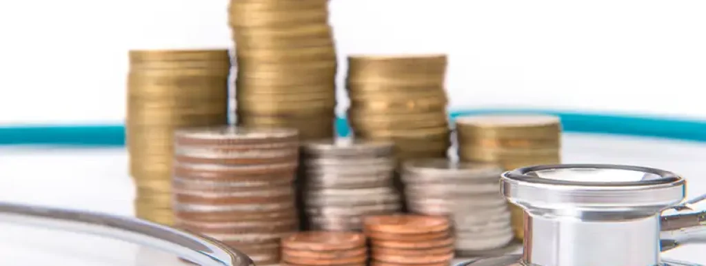 moedas-e-dinheiro-em-cima-de-mesa-com-aparelho-medico moedas-e-dinheiro-em-cima-de-mesa-com-aparelho-medico